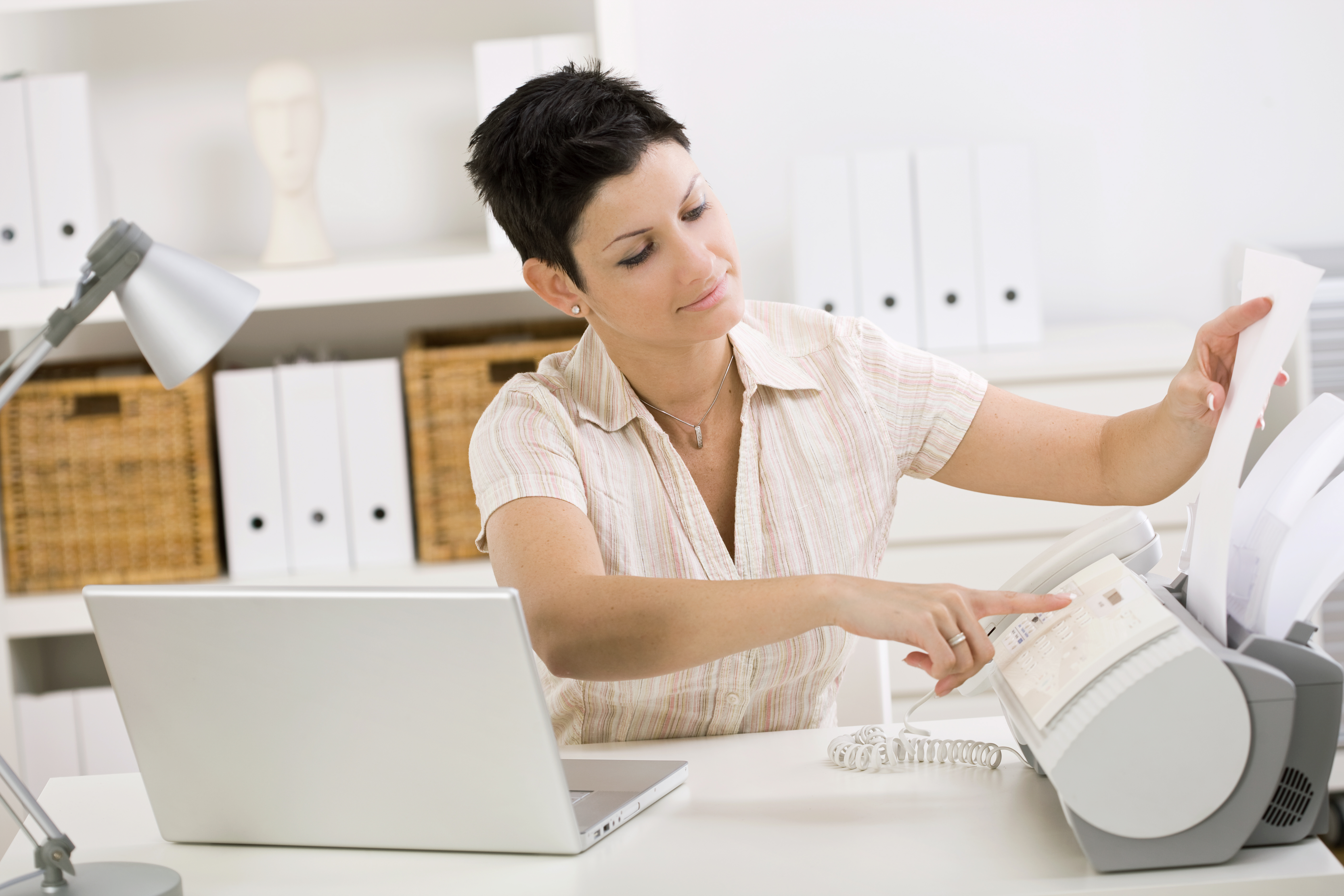 Woman using fax machine at home office.